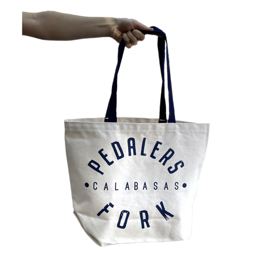 White tote bag with blue strap, Pedalers Fork logo with Calabasas in between
